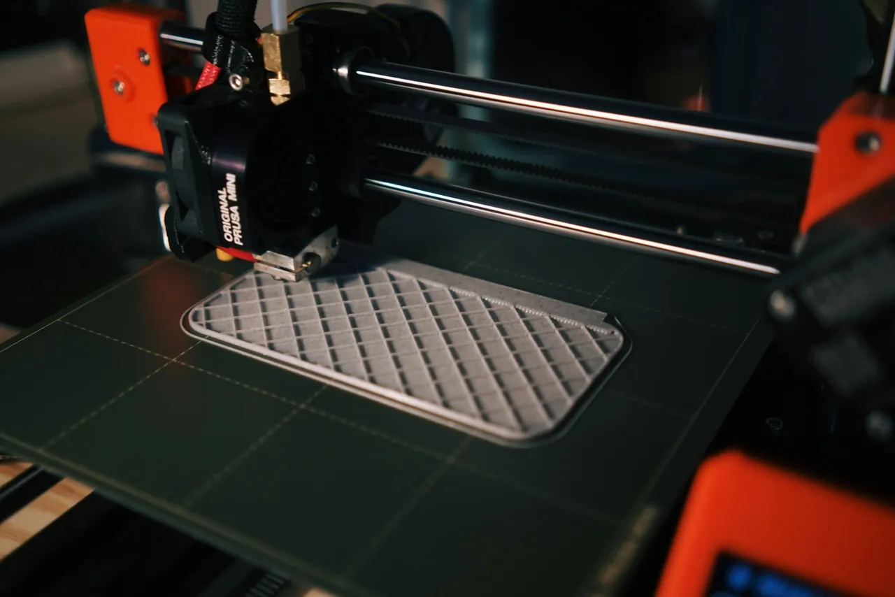 A 3D printer building a flat part layer by layer on the print bed